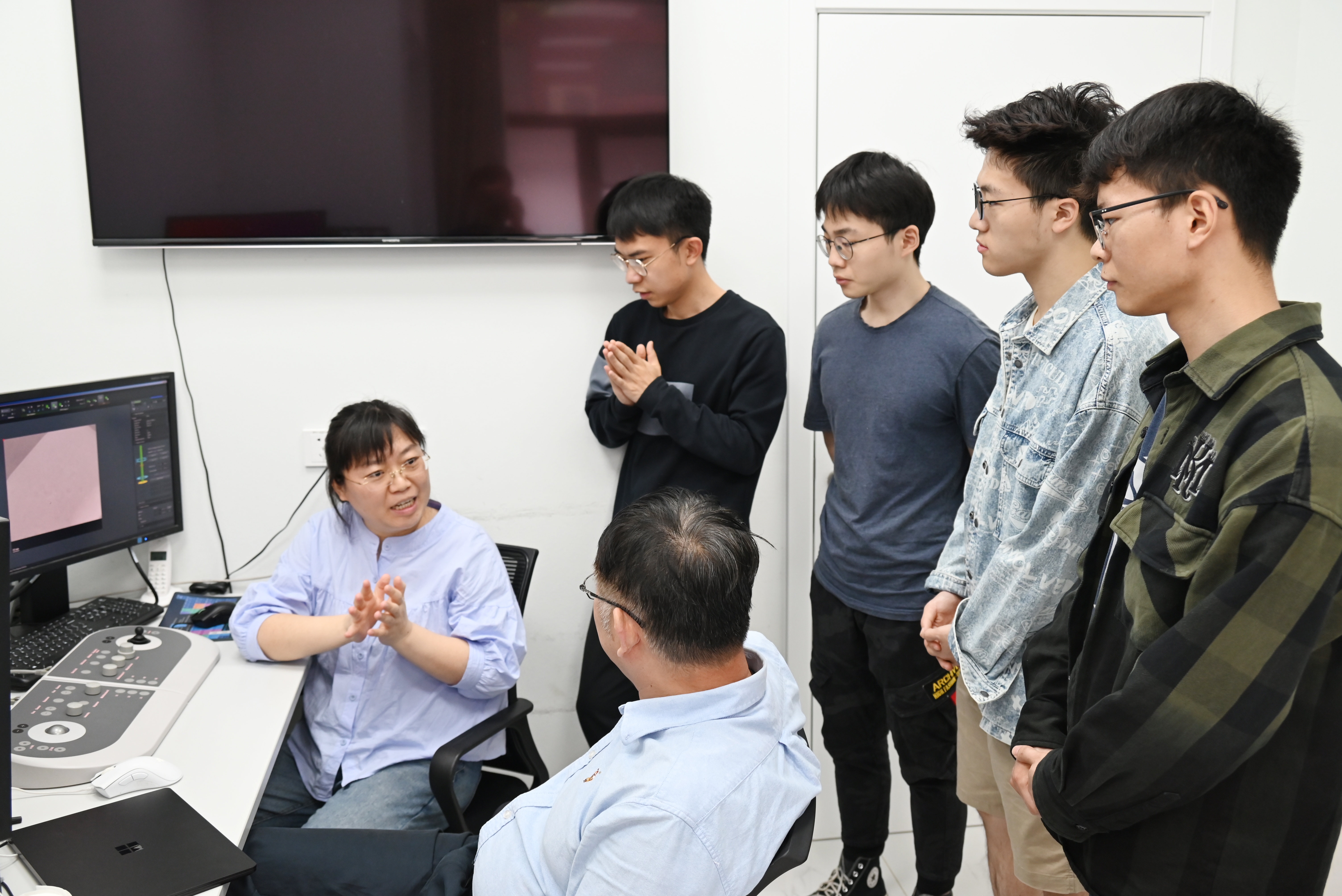 20231114-魏飞教授科研报道-供图-魏飞和陈晓在实验室交流,同学们在一旁认真学习.jpeg